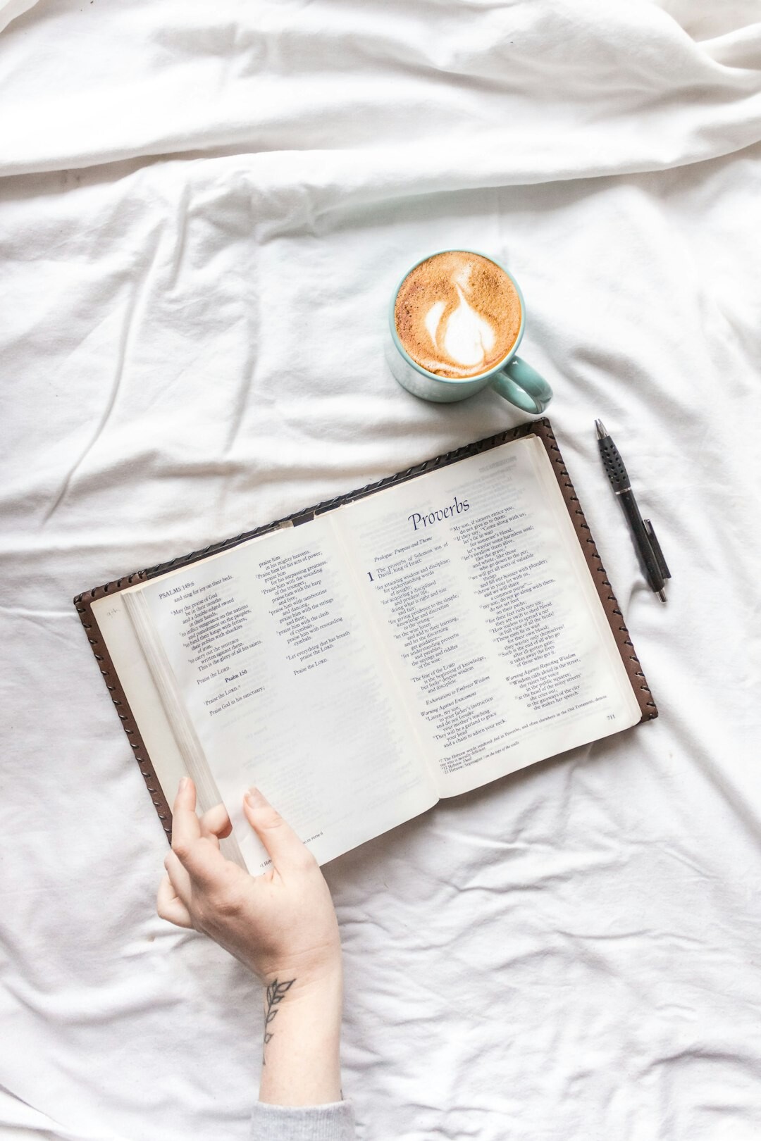 Hands writing personal goals in a notebook next to a cup of coffee